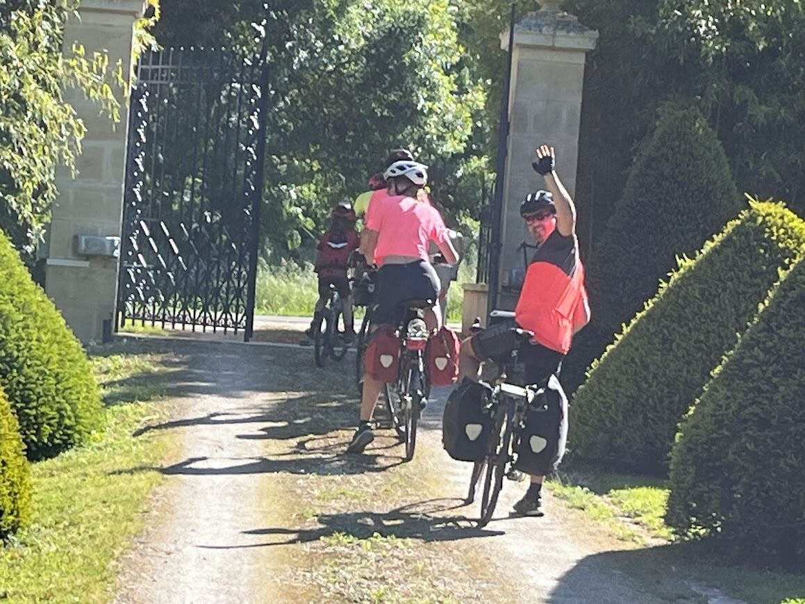 En grupp cyklister på en asfalterad stig, omgiven av grönska.