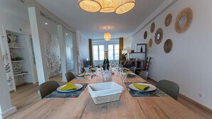 Un comedor con una larga mesa de madera dispuesta para seis personas, rodeada de sillas.