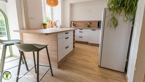 Una cocina moderna con encimera de madera, armarios blancos y una planta colgante.