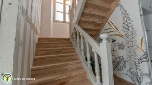 Una escalera de madera con balaustres blancos y un mural floral en la pared.