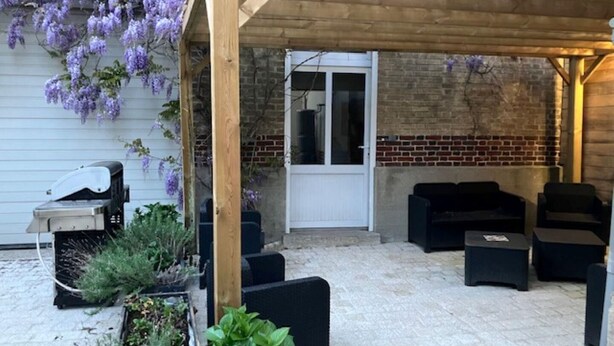 A covered patio with outdoor furniture, a grill, and purple flowering vines. - L'appart' de la Goutte D'or (Avize)