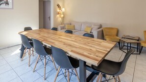 A modern dining area with a wooden table and chairs, a sofa, and a chandelier. - L'appart' de la Goutte D'or (Avize)