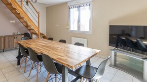 A dining area with a wooden table, black chairs, a chandelier, a TV, and a staircase. - L'appart' de la Goutte D'or (Avize)