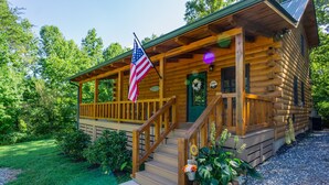 A wooden cabin with a porch, a staircase, and an American flag. - Cozy Cabin Minutes to Helen and best hiking trails in the area! Pet Friendly! (Cleveland)