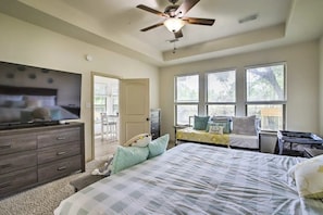 A bedroom with a large bed, a TV, a ceiling fan, and a window with blinds. - Welcoming Montgomery Home in April Sound Gated Community! (Montgomery)
