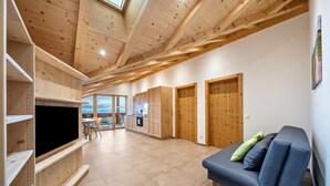 A spacious living area with a wooden ceiling, built-in TV, and a blue sofa.