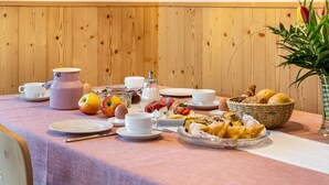 A breakfast table with various food items, a teapot, cups, and a vase with flowers.