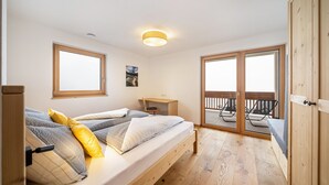 Une chambre avec un lit, un bureau et un balcon équipé de chaises.