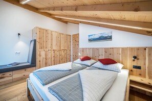 A bedroom with a wooden headboard, a bed with multiple pillows, a bench with a book, and a wall-mounted picture.
