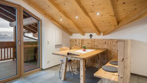A wooden dining table with chairs, a small plant, and a cross on the wall.