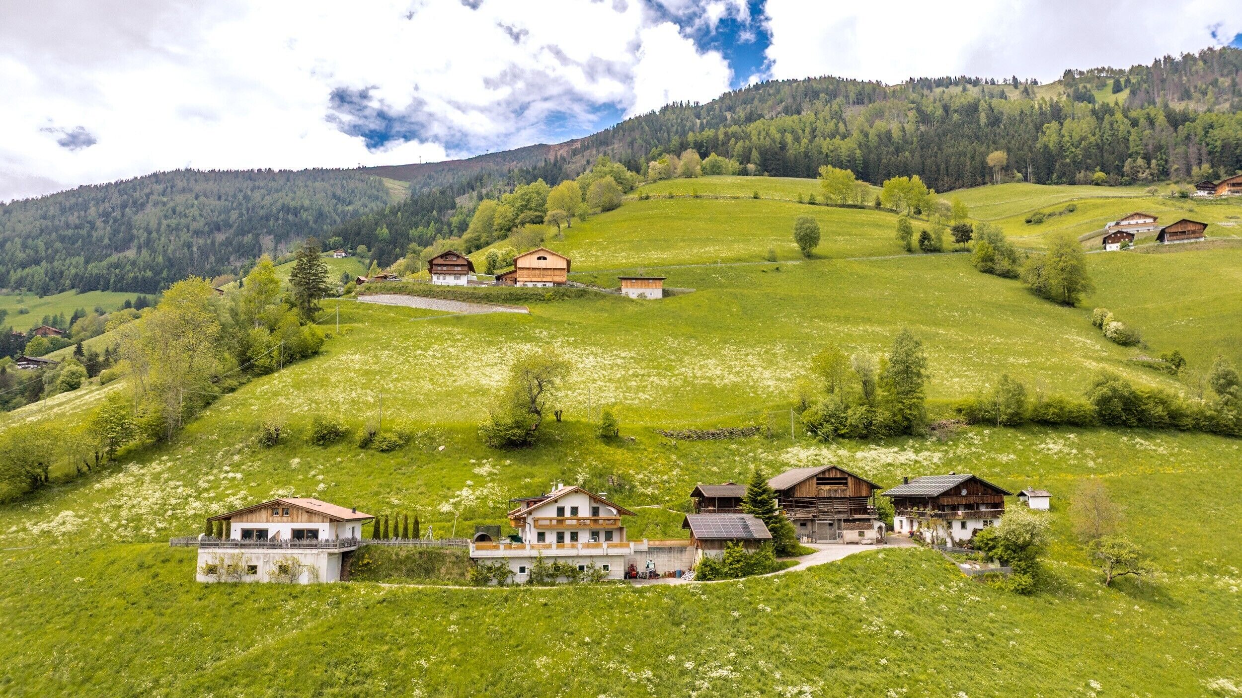 Un village rural avec des maisons traditionnelles en bois, un pont et un paysage montagneux en arrière-plan.