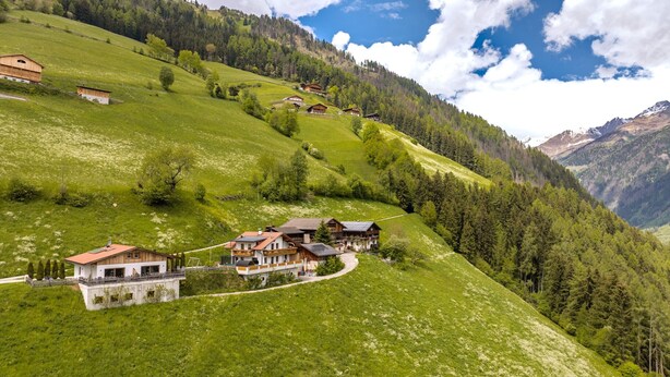 A hillside with multiple wooden chalets, a paved path, and a view of the surrounding forest and mountains. - Apartment 'Tratterhof Apt Eidechsspitze' with Mountain View, Private Terrace and Wi-Fi (Vandoies)