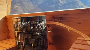 A wooden cabin with a view of snow-capped mountains, a stone fireplace, and a wooden bench. - Apartment 'Tratterhof Apt Eidechsspitze' with Mountain View, Private Terrace and Wi-Fi (Vandoies)