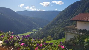 A mountainous landscape with a valley, a wooden fence, and a building with a red roof. - Apartment 'Tratterhof Apt Eidechsspitze' with Mountain View, Private Terrace and Wi-Fi (Vandoies)