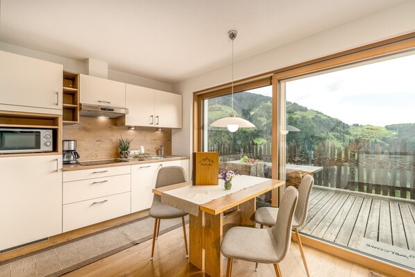 Une cuisine moderne avec un coin repas, un plancher en bois et une grande fenêtre donnant sur un paysage pittoresque.