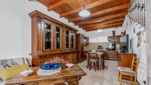 A spacious kitchen with wooden cabinets, a dining table, and chairs. - Apartment 'Casa Rustica' with Private Terrace, Wi-Fi and Air Conditioning (Gonnesa)