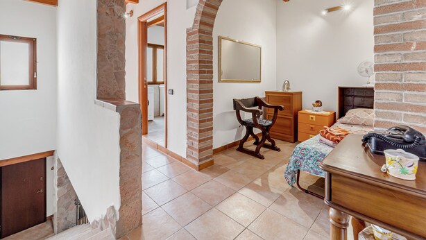 A bedroom with a stone fireplace, wooden beams, a bed, a desk, and a chair. - Apartment 'Casa Rustica' with Private Terrace, Wi-Fi and Air Conditioning (Gonnesa)