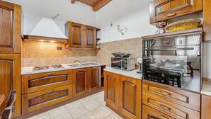 A kitchen with wooden cabinets, a stove, a microwave, and a refrigerator. - Apartment 'Casa Rustica' with Private Terrace, Wi-Fi and Air Conditioning (Gonnesa)