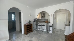 Una cocina amplia con piso de mármol, un pequeño árbol de Navidad y una barra con taburetes.