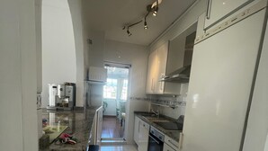 Una cocina con gabinetes blancos, un refrigerador, un microondas y un lavamanos.