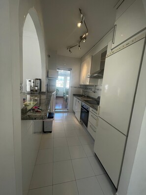 A kitchen with white cabinets, a refrigerator, a microwave, and a sink. - Apartment 'Atico Gran Vista Peñoncillo' with Sea View, Wi-Fi and Air Conditioning (Torrox Costa)