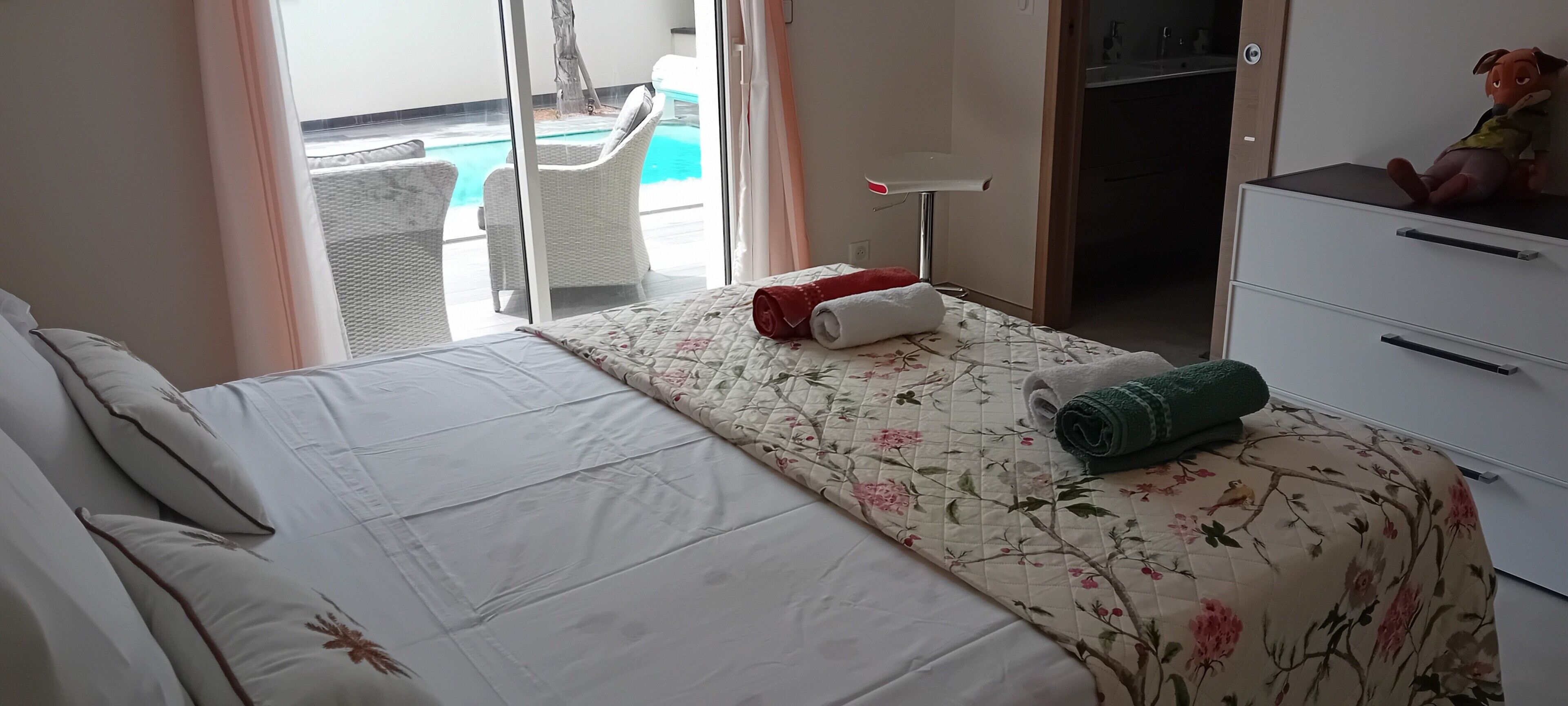 A hotel room with a bed, a desk, a chair, and a view of a pool.