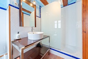 A bathroom with a white sink, mirror, and glass shower enclosure.