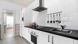 A modern kitchen with white cabinetry, a black countertop, a stainless steel sink, and a built-in oven. - Casa la Viña with pool, Wi-Fi, and air conditioning (Chiclana de la Frontera)