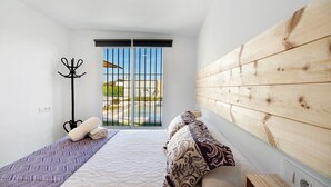 A bedroom with a bed, a coat rack, and a view of a pool and greenery. - Casa la Viña with pool, Wi-Fi, and air conditioning (Chiclana de la Frontera)