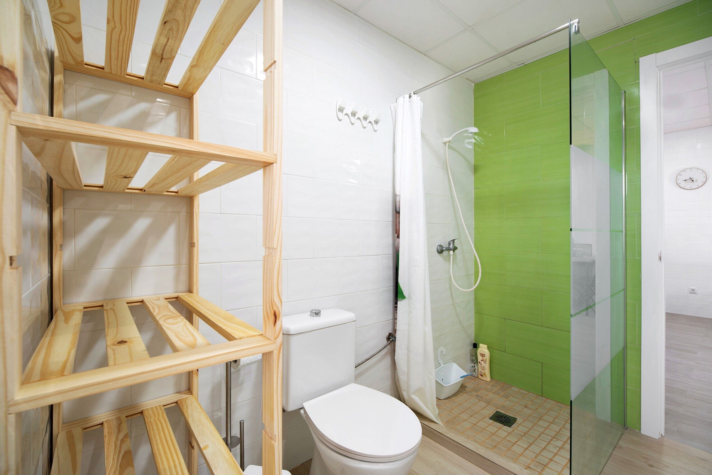 Une salle de bain avec des toilettes, une douche et des étagères en bois.