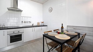 A modern kitchen with white cabinets, a stainless steel range hood, and a dining table set with placemats and chairs. - Casa la Viña with pool, Wi-Fi, and air conditioning (Chiclana de la Frontera)