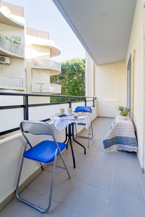 A balcony with a table set for two, two chairs, and a small potted plant. - ParkApart Rhodes Town (Rhodes)