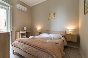 Une chambre à coucher comprenant un lit, des tables de chevet, un bureau et un appareil de climatisation.