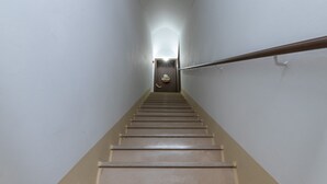 A straight flight of stairs with a handrail on the right, leading to a door at the top.