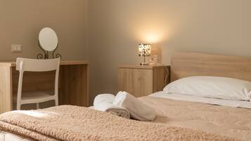 A bedroom with a bed, a chair, a nightstand with a lamp, and a mirror.