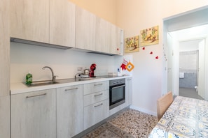 Une cuisine de taille réduite, équipée d’un évier, d’une cuisinière et de placards.