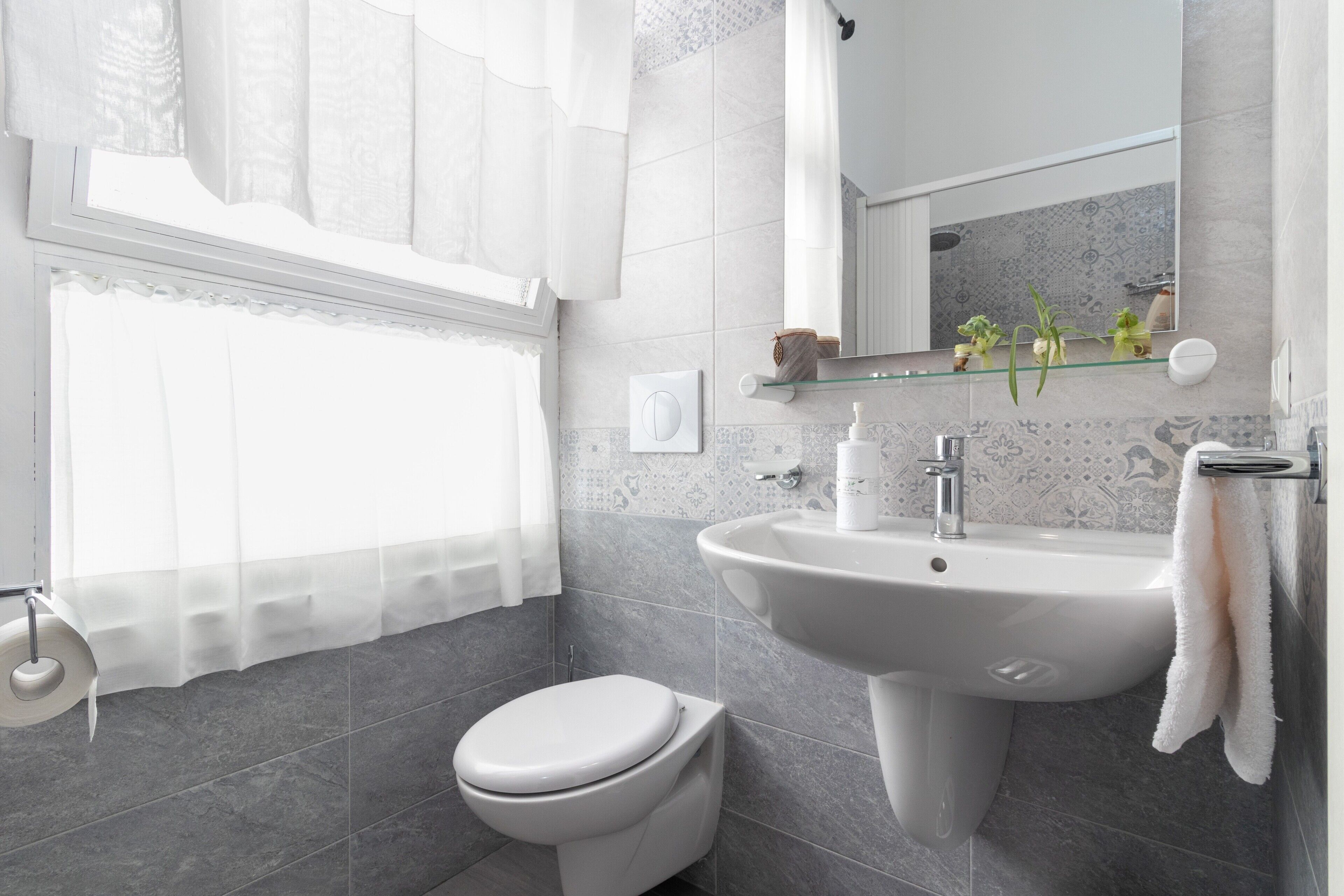 A bathroom with a toilet, sink, and mirror.