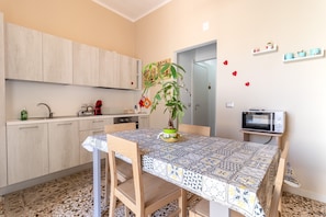 Une cuisine équipée d’une table à manger, de placards, d’un four à micro-ondes et d’une plante en pot.
