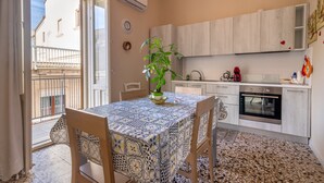 A kitchen with a dining area, a potted plant, and a view of the outside.
