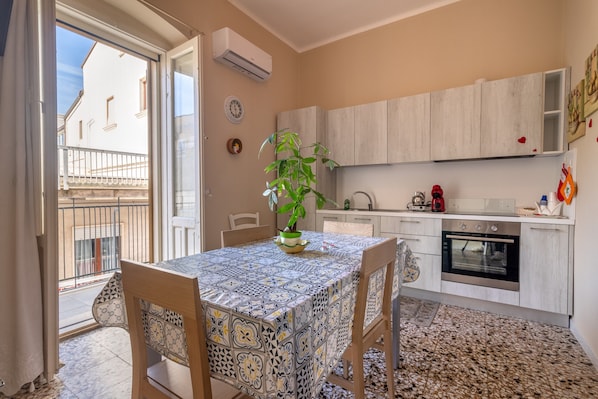 Une cuisine avec un coin repas, une plante en pot et une vue sur l’extérieur.