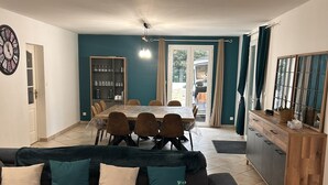 A living room with a dark grey sectional sofa, a wooden coffee table, and a dining area with a table and chairs.
