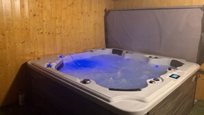 A hot tub with a control panel and a cover, set against wooden walls.