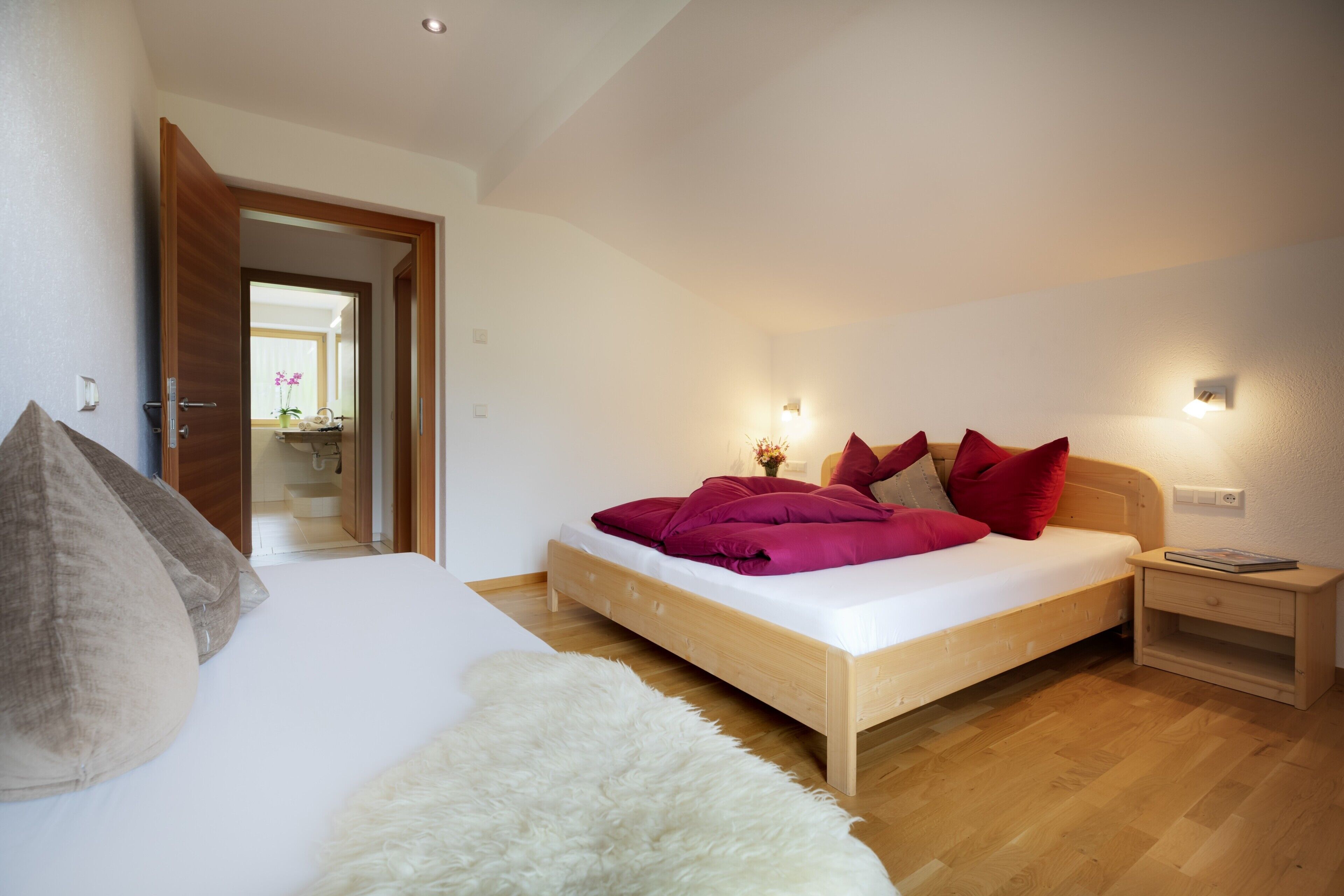 Un dormitorio con cama, mesita de noche, alfombra mullida y suelo de madera.