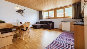 Un intérieur moderne avec un plafond en bois, un coin repas, un canapé et une cuisine.