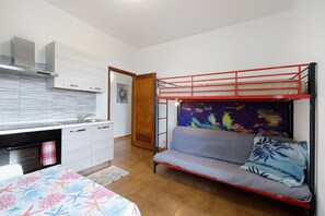Habitación pequeña con literas, kitchenette y una zona de estar.