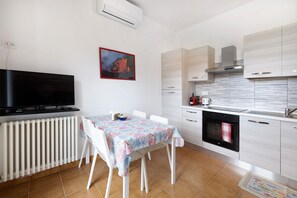 Una cocina moderna con armarios blancos, horno empotrado y un comedor con mesa y sillas.