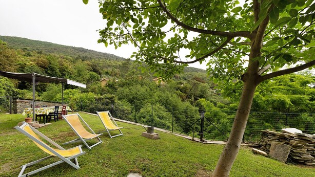 Un espace extérieur verdoyant, avec des chaises longues et une structure en pierre.