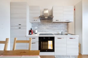 A modern kitchen with a built-in oven, a stovetop, and a sink. - Apartment 'Elena E Joerg 2' with Mountain View, Shared Garden and Wi-Fi (Vezzi Portio)