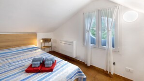 A bedroom with a bed, a nightstand, a window with curtains, and a radiator. - Apartment 'Elena E Joerg 2' with Mountain View, Shared Garden and Wi-Fi (Vezzi Portio)