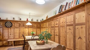Een houten eethoek met een tafel, stoelen, een fruitmand en een dartbord.